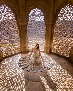 a woman is sitting on the floor in an ornate room with large windows and shadows