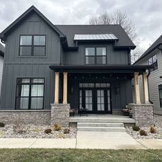 a large gray house with two story windows and stone steps leading up to the front door