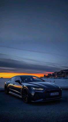 a black sports car parked in front of the ocean