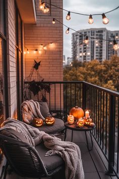 a balcony decorated for halloween with lights and pumpkins on the table, two chairs