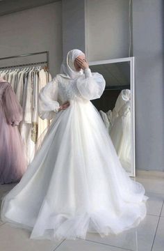 a woman standing in front of a closet full of wedding gowns and dresses on hangers