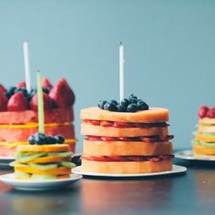 there are three cakes with fruit on them and candles in the shape of hamburgers