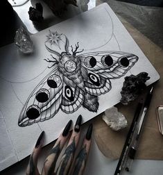 a woman's hand with black and white tattoos on it, next to a drawing of a moth