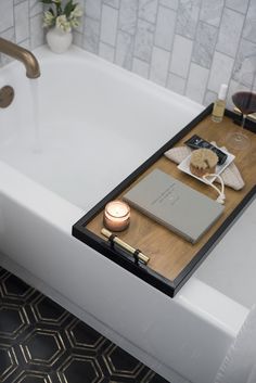 a bath tub with a wooden tray on the side and a candle in front of it