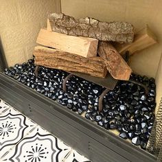 a pile of wood sitting on top of black rocks in a room next to a wall