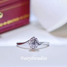 The image focuses on a classic 1 carat solitaire engagement ring. A sizable 6.5 millimeter round cut simulated diamond in a slender knife edged sterling silver band catches the light on a finger. Dainty Promise Ring, Rings Pandora, Bypass Engagement Ring, Engagement Ring Dainty, Snowflake Ring, Silver Promise Rings, Solitaire Rings, Swirl Ring