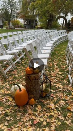 rows of white folding chairs with pumpkins and lantern on the ground in front of them