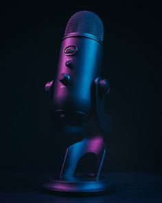 a purple and blue microphone on a black background with the light reflecting off it's side