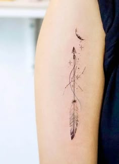 a woman's arm with an arrow and feather tattoo on the left side of her arm