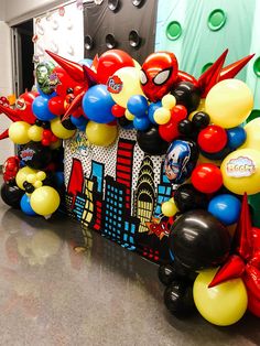 some balloons are in the shape of spiderman and other things on display at a party