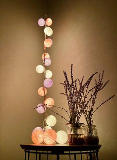 a table topped with vases filled with flowers next to a string of paper lanterns