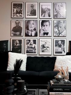 a living room filled with black and white pictures on the wall above a couch next to a coffee table