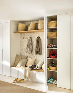 a white closet filled with lots of clothes and shoes next to a wall mounted coat rack