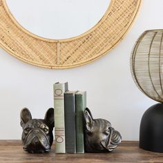 a dog statue sitting next to two books on a wooden table in front of a mirror