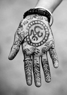 a person's hand with tattoos on it and an om sign painted on the palm