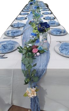 a long table is set with blue plates and place settings for the guests to sit at