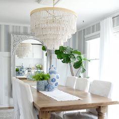 a dining room table with white chairs and a chandelier hanging from the ceiling