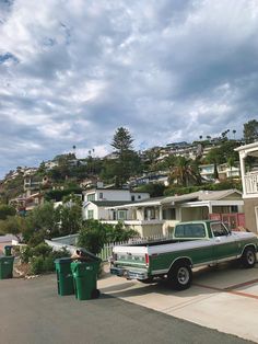 a truck is parked in front of some houses on a hill side with trees and bushes