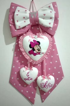 a minnie mouse bow with two hearts hanging from it's side on a wall