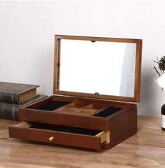 an open wooden box on a table next to some books