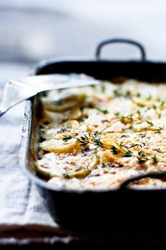 a casserole dish with cheese and vegetables in it sitting on a tablecloth