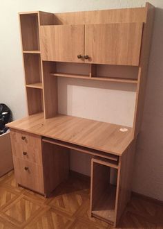 a wooden desk sitting on top of a hard wood floor next to a white wall