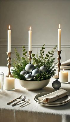 a table with candles, plates and silver ornaments on it is set for an elegant christmas dinner