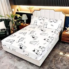 a white bed with black and white doodles on it, next to a lamp