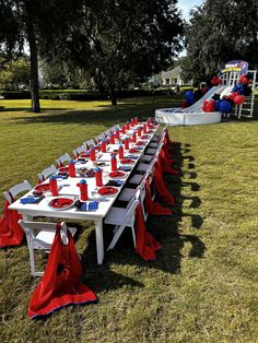 a long table set up with red and white plates, napkins and cups on it