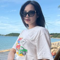 a woman wearing sunglasses standing next to the ocean