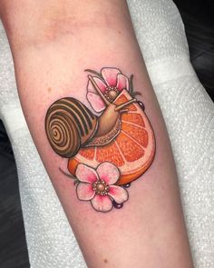 an orange slice with a snail on top of it and flowers in the middle of its arm