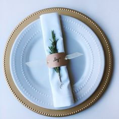 a white plate topped with a napkin covered in greenery next to a knife and fork