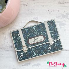 a handbag sitting on top of a white table next to a pink potted plant