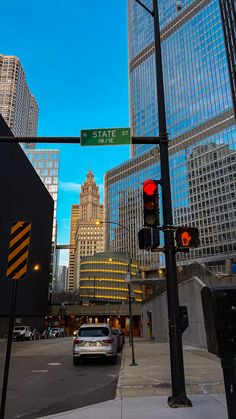 a traffic light on state street in front of tall buildings and skyscrapers at dusk