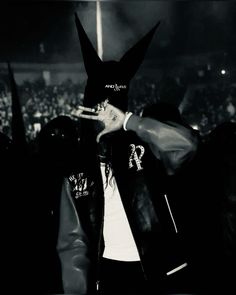 a man wearing a bunny mask and jacket in front of an audience at a concert