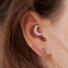 a close up of a person wearing an ear cuff with a crescent design on it