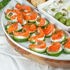 a platter filled with cucumbers, olives and crackers topped with smoked salmon