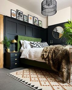 a bedroom with black walls and white bedding, green headboard, potted plants, rugs and pictures on the wall