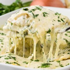 a spoon full of cheese and spinach dip being lifted from a casserole dish