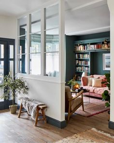 a living room filled with furniture and bookshelves next to a doorway that leads to a balcony