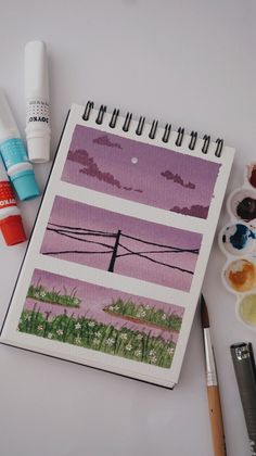 an art project with watercolors, paintbrushes and paper on the table