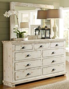 a white dresser sitting in front of a mirror