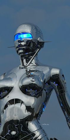 a silver robot with blue eyes standing in front of the camera on a clear day