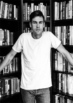 a man standing in front of a bookshelf with his hands on his hips