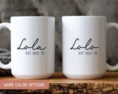 two white coffee mugs with black ink on them