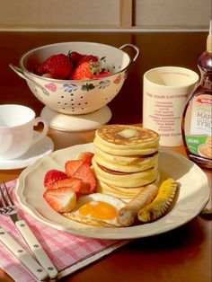 pancakes, strawberries, and eggs on a plate with syrup in a colander