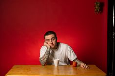 a man sitting at a wooden table with a cup in front of him