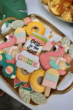 decorated cookies in the shape of flamingos are on a tray next to other food