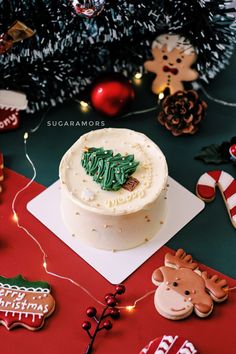 a decorated christmas cake sitting on top of a table next to cookies and other decorations