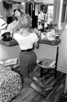 a woman standing in front of a mirror brushing her hair